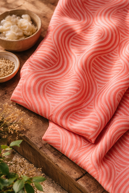 Pink fabric with wavy pattern on a wooden surface